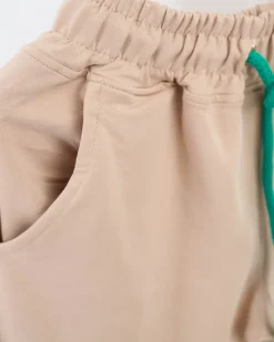 Royalfashion Beżowe damskie spodnie dresowe z kolorową naszywką